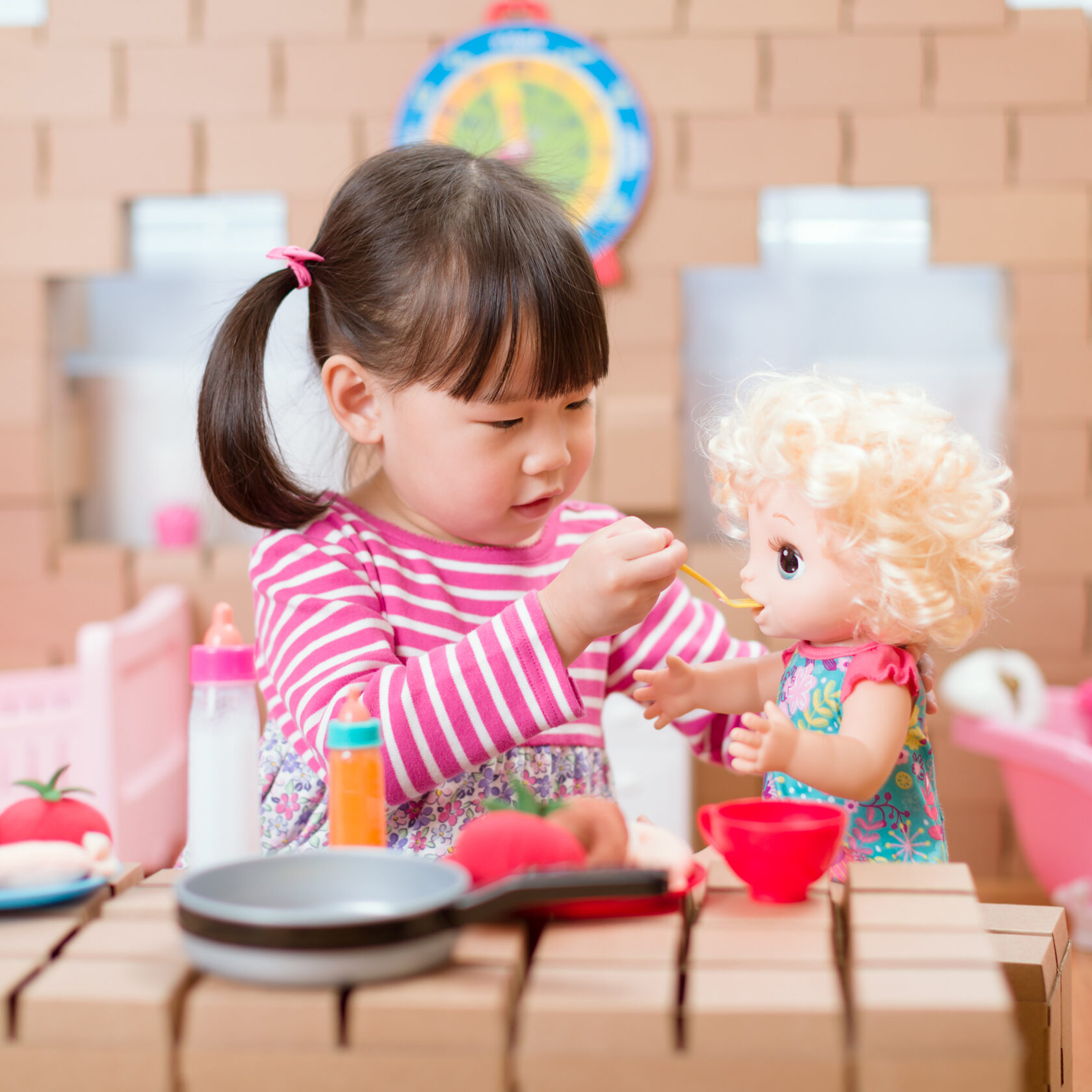 young girl pretend play babysitting with baby doll at home